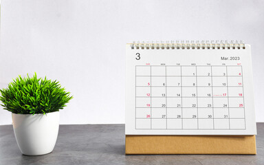 March 2023 Desktop calendar for planners and reminders on wooden table with plant pots on a white...