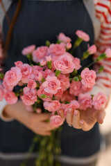 selective focus of bunch of small pink carnation flowers in woman hands. Close-up