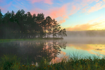 a wonderful sunrise picture with a gorgeous sky, fog covering the surface of the lake, black...