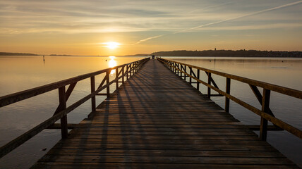 Fototapeta na wymiar Wooden walkway in the foreground. Middle ground the Baltic Sea. Clear sky at sunset. Harrislee, Flensburg, Fjord, Germany