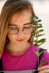 Close-up portrait of woman with closed eyes and sprig of Oxypetalum in her hand