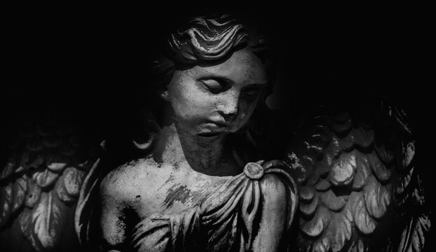 Death. Sad angel against black background as symbol of pain, fear and end of life. Horizontal image.