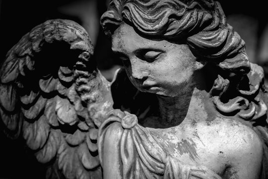 Death. Sad angel against black background as symbol of pain, fear and end of life. Horizontal image.