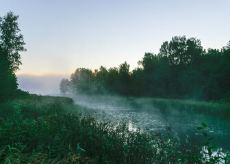 autumn morning by the lake, fog over the surface of the water, a moment before sunrise