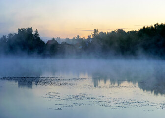 autumn morning by the lake, fog over the surface of the water, a moment before sunrise