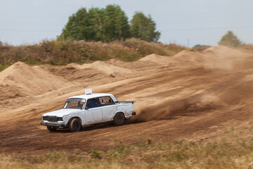 Obraz na płótnie Canvas Rally off-road car make a turn with the clouds and splashes of sand, gravel and dust during rally championship