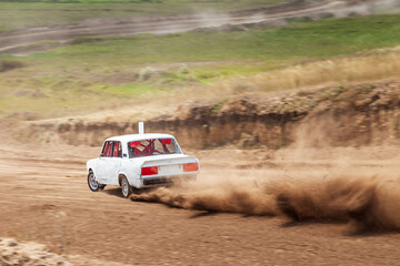 Rally off-road car make a turn with the clouds and splashes of sand, gravel and dust during rally championship