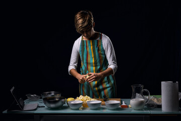 Working in the kitchen. Half-length photography. Cooking an apple pie, White glass table. Culinary ingredients. Chef's knife. Black background.