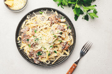 Mushroom Tagliatelle Pasta with parmesan cheese and cream sauce on white background, top view. Prepared italian pasta with champignon on gray plate