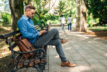 Fototapeta premium Serious adult businessman or freelancer, using laptop, working outside.