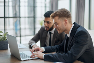 two professional businessmen discussing and using desktop computer in office