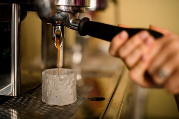 Close-up of coffee machine making espresso and hot drink flows into grey cup