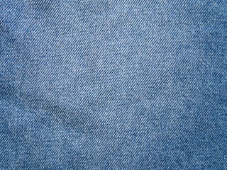 Denim fabric texture of a piece of cloth. Empty background of a textile material. Clothing part in a close-up view. Abstract backdrop of woven fibers. Blue jeans cloth pattern structure.