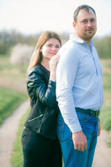 Fototapeta premium A couple of a tall young man and his girlfriend with long blond hair are walking in the city in nature. Emotions and feelings. Life style