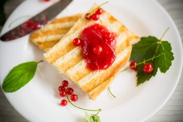 fried bread croutons for breakfast with redcurrant jam in a plate with berries