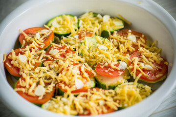 raw zucchini and tomatoes sliced with cheese, prepared for baking