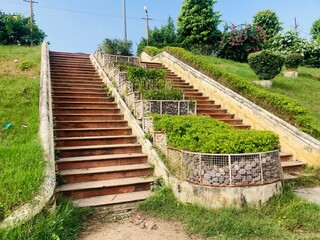 Fototapeta na wymiar Landscape of long winding stairs in the town, long stone steps iin a park leading up a hill with metal handrail