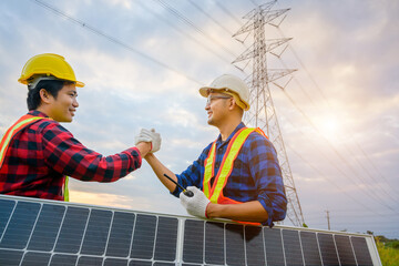 2 male electrical engineers stand at a power station shaking hands at a power plant and solar...