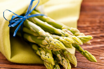 Green fresh raw asparagus bundle offered as close-up on a wooden board