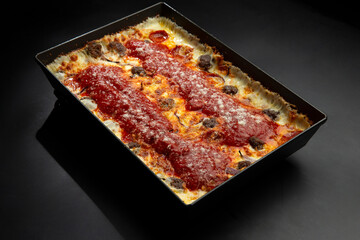 Detroit pizza with meat and sauce on an iron tray