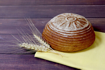 Freshly baked bread and ears of rye lie on a wooden board. Harvest. Selective focus