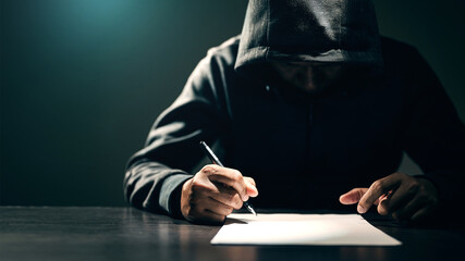 Male thieves sign confession on paper to acknowledge the allegations.