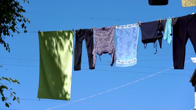 Clothes drying on a clothesline. Different types of clothes hanging on a clothesline․ Լaundry hanging out to dry outdoors․  clothes dries on a rope against a blue sky background․ 