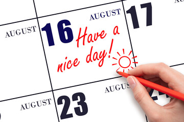The hand writing the text Have a nice day and drawing the sun on the calendar date August 16