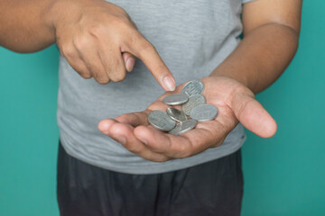 a young asian man holding and counting his Indonesian coins