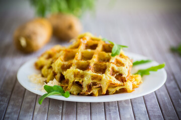 fried potato waffles with cheese in a plate on wooden table.