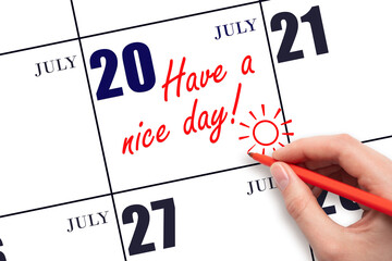 The hand writing the text Have a nice day and drawing the sun on the calendar date July 20