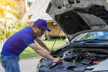 A man checking and fixing a broken car on the side of the road. Problems with broken cars on the...