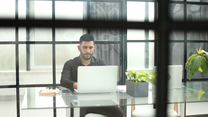 Fototapeta premium Businessman with glasses in the office working on a laptop