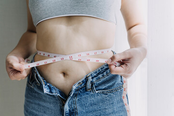Beautiful fat woman with tape measure She uses her hand to squeeze the excess fat that is isolated on a white background. She wants to lose weight, the concept of surgery and break down fat under the