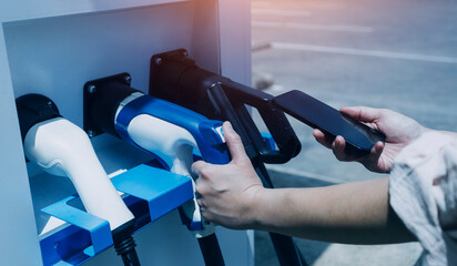 Hand plugging in a charger in an electric car socket.Electric car or ev is charging at station