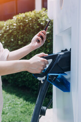 Hand plugging in a charger in an electric car socket.Electric car or ev is charging at station