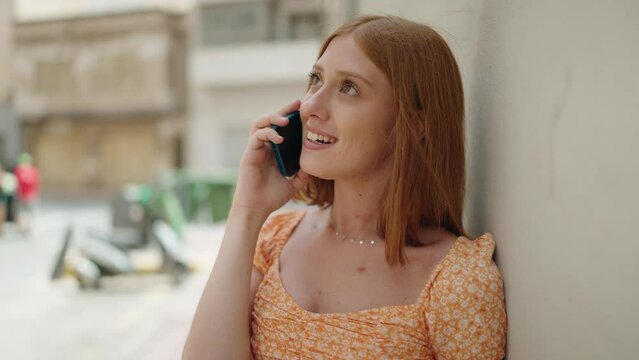 Young redhead woman smiling confident talking on the smartphone at street