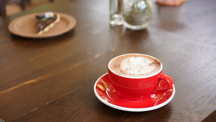 Latte art hot coffee with tulip milk latte art on top of white ceramic glass set on wood table in coffee shop Hot chocolate drink with white foam and cacao brown powder on top in transparent short cup