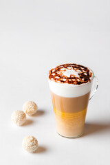 Latte macchiato in a tall glass on a white background. Cafe latte layered with milk in a high drinking glass. Minimalism. Сopy space