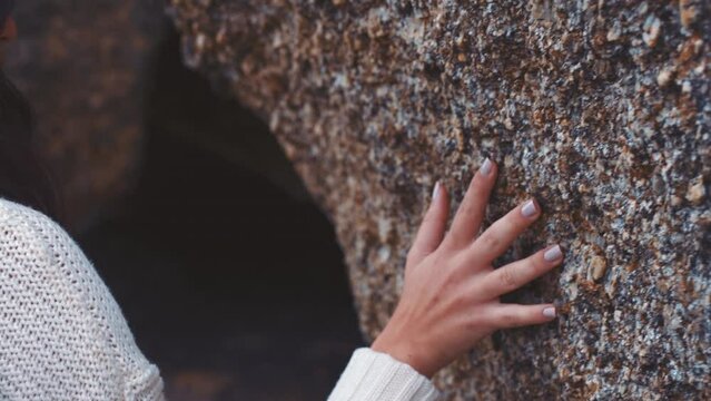 Nature, mountain cave and touch of woman hand feeling texture or surface of rock. Travel, hiking and ecology or speleology adventure, discovery and exploration with girl touching stone wall formation