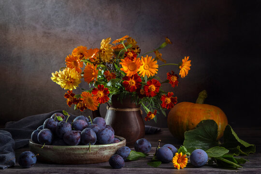 Still life with plums and a bouquet of orange flowers