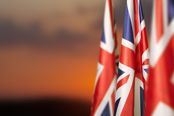National flags of United Kingdom on a flagpole on sunset sky background. Lowered UK flags....