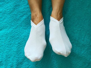 Female legs on a blue background. Women's feet in white socks.