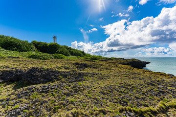 Fototapeta na wymiar 岩のある真夏の海と灯台