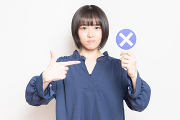 NGのプレートを見せている若い女性