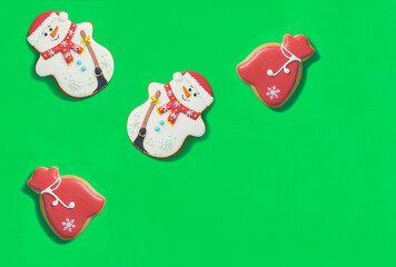 Christmas gingerbread in the shape of gift bag and snowman on the green background. Top view. Copy space.