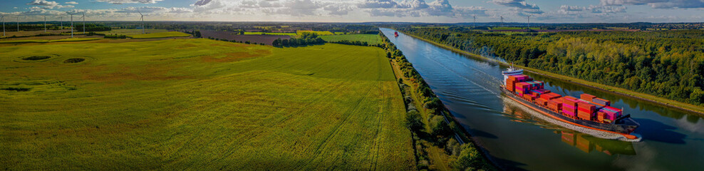 Cargo ship on the Kiel Canal with flourishing agriculture and renewable energy production in the...