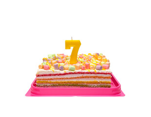 multi-colored rainbow cake in a transparent box with a red bow. Birthday cake with candle number 7 isolated on white background.