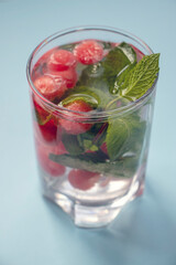 Water infusion with watermelon balls and mint on a blue background.