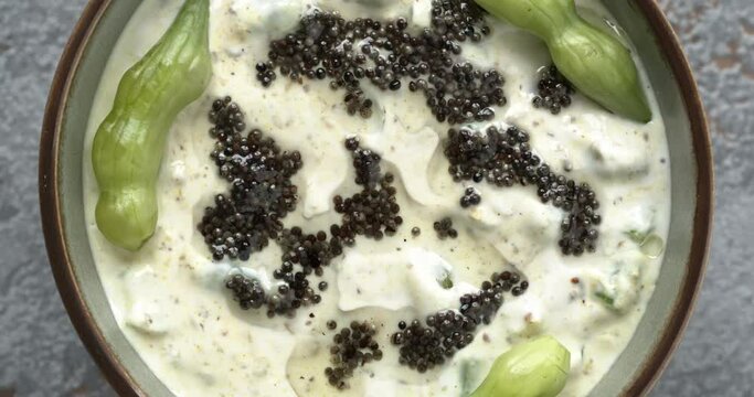 Mogri Raita tempered with black mustard seeds oil and spices: kala namak (black salt), Indian mustard powder and roasted cumin. Table spin, clos-up view.
